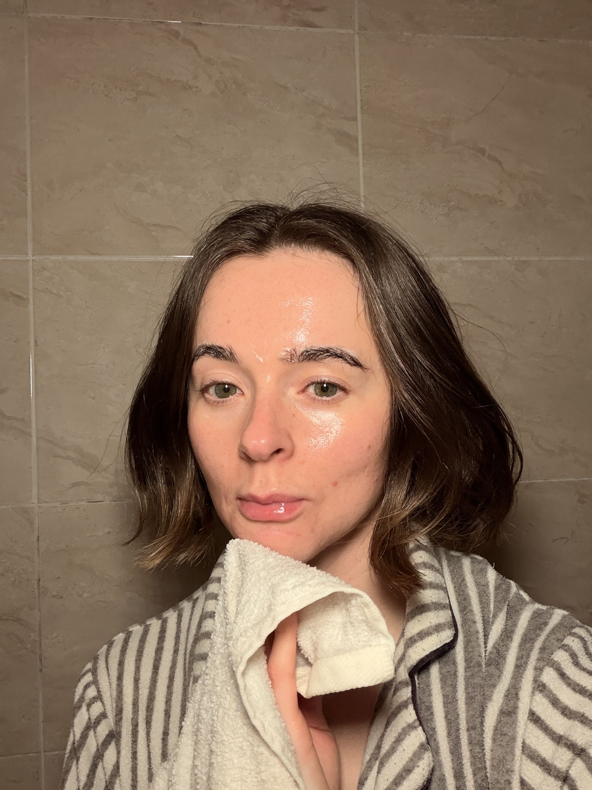A selfie of Grace Day in a stripy dressing gown using a cleansing flannel to clean her skin