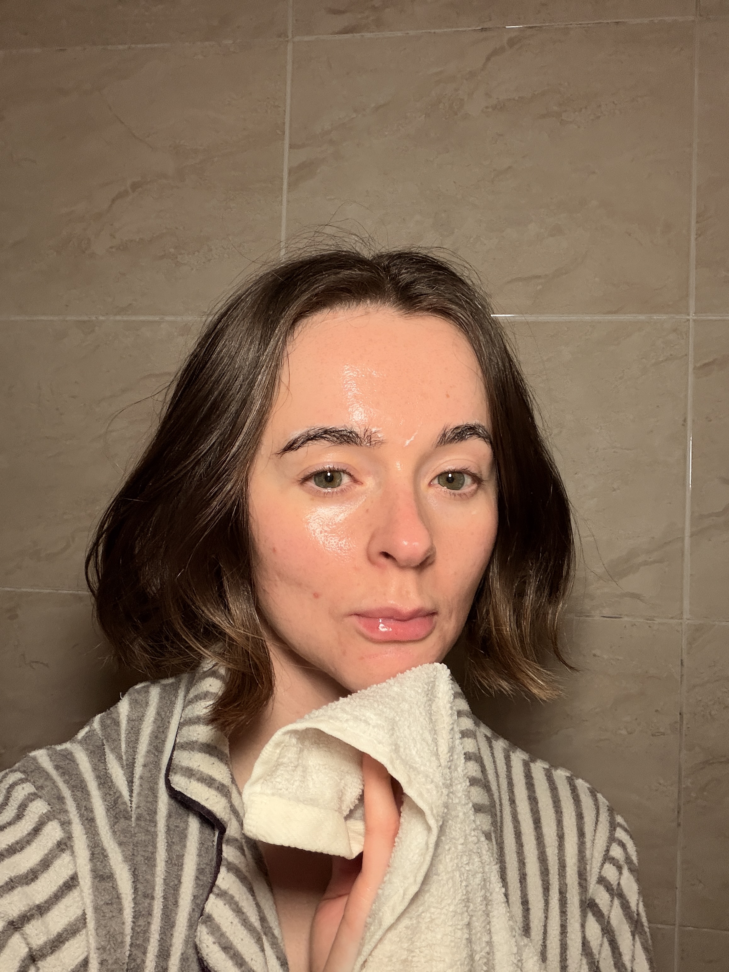 A selfie of Grace Day in a stripy dressing gown using a cleansing flannel to clean her skin
