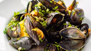 bowl of muscles with green herbs as topping