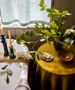 bathroom with side table, ochre yellow tablecloth and green gingham curtain