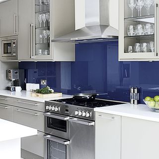 cooking area with blue and grey kitchen with chimney