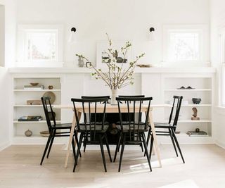 white dining room with black dining chairs and a wooden dining table