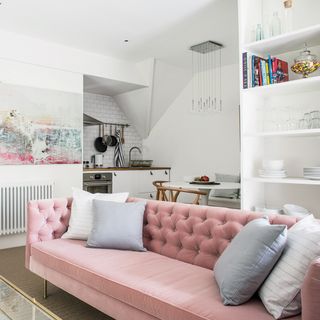 White open plan kitchen living room with pink button-back sofa