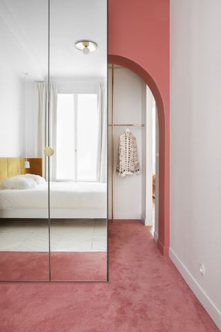 A bedroom with mirrored cabinets and pink carpet