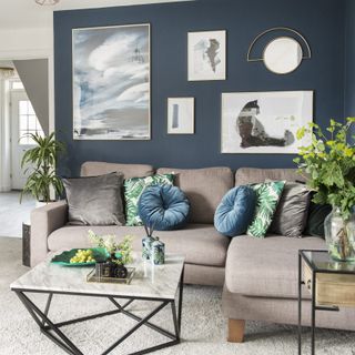living room with blue wall frames on wall and cream colour sofa with cushion