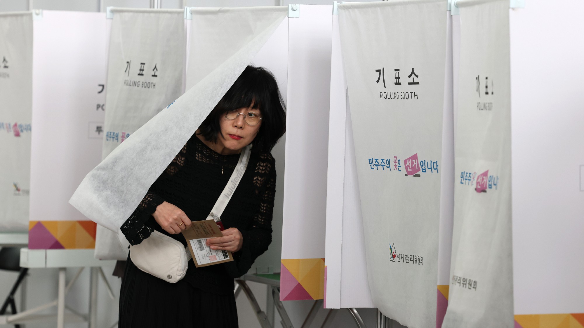 A woman comes out of a booth in a polling station in Incheon, South Korea