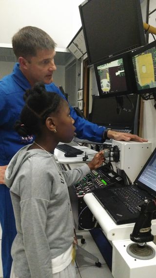 Canadian astronaut Jeremy Hansen demonstrates the Canadarm2 simulator to a young girl at the Canadian Space Agency headquarters near Montreal.