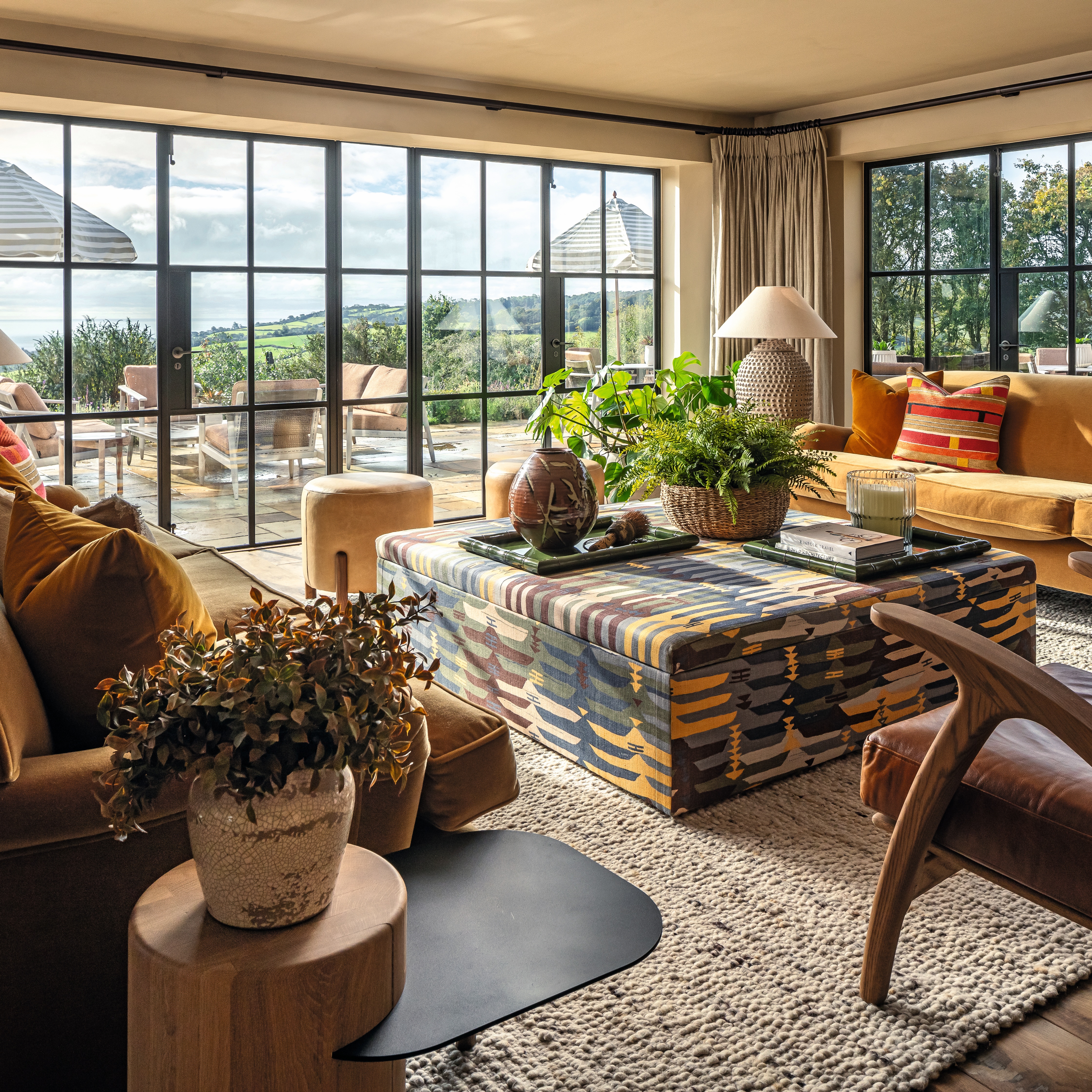 A loft-style building with industrial floor-to-ceiling windows houses a contemporary design hotel with eye-catching, colorful fabrics, textural rattan rugs, wooden furniture, and plenty of natural light.