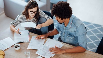 Young couple at a table creating a budget with bills and other paperwork