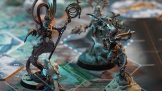 Two Slaanesh daemons crowd together with an Ioneth Deepkin behind them on the Warhammer Underworlds: Deathgorge board