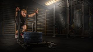 Man pushes weighted sled in gym