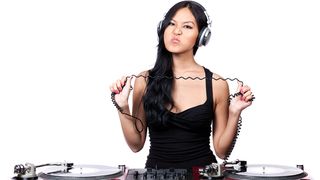 A young female DJ stretching out the cord from her headphones and making a mean face.