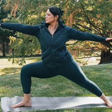 Model Ashley Graham working out and doing yoga in the best plus-size leggings outside on yoga mat.