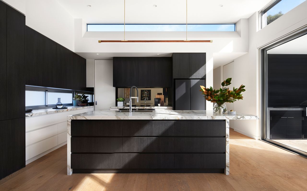 A kitchen in black and white, with a large island in the middle