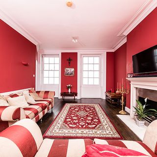 red living room with wooden flooring and red sofa