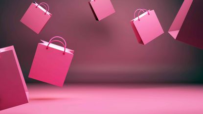 pink shopping bags falling in front of pink backdrop