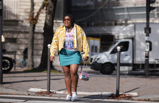 Gabriella Karefa-Johnson in a blue mini skrit, tee shirt, and yellow jacket.