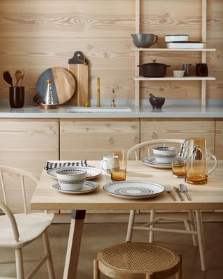 Blond wood kitchen with matching open shelving unit and large dining table