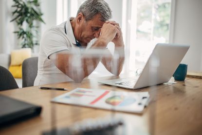 Man sitting in front of a computer looking concerned. 