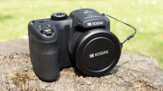 Kodak PixPro AZ255 digital camera in black on a stone surface in front of a green background outside