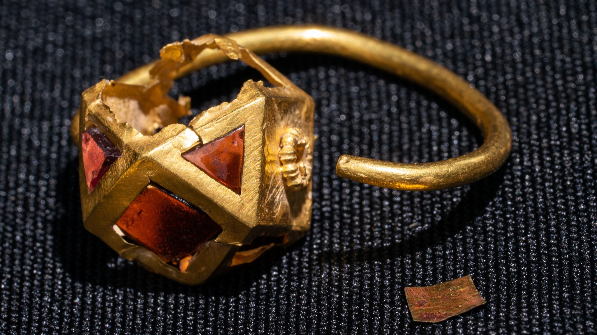 A close-up of a gold ring with red jewels