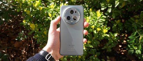 Honor Magic 5 Pro helf in the hand in front of a bush
