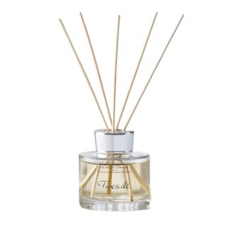 A glass reed diffuser bottle with wooden reeds