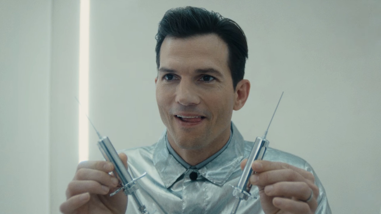 Ashton Kutcher's The Corporation holding two syringes in The Beauty Season 1