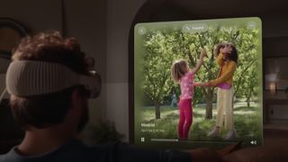 Een man zit in een woonkamer met de Apple Vision Pro-headset op zijn hoofd en hij bekijkt een familieherinnering