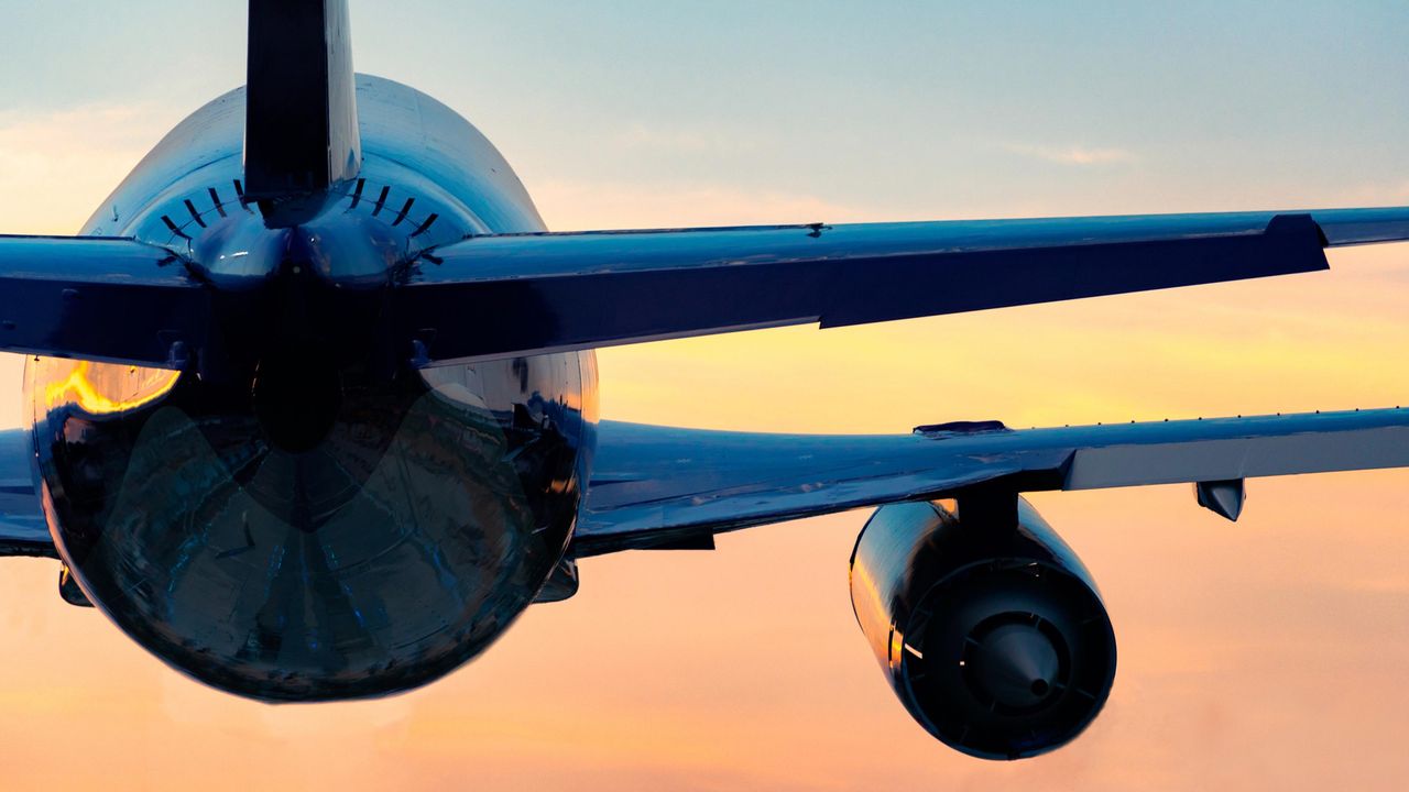 The rear of a jet airliner as it takes off at sunset