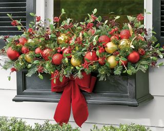 Christmas window decor ideas with a window box filled with red and gold baubles and a red ribbon