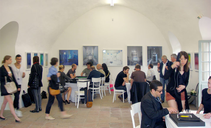 A room with tables, chairs, people and wall paintings.