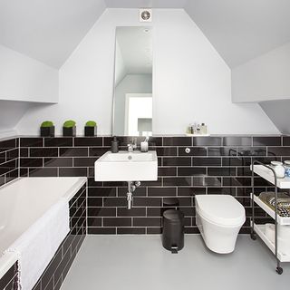 bathroom with grey tiled walls and bathtub