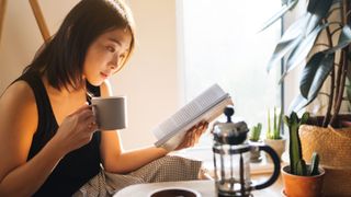 Woman drinking a coffee and reading a book