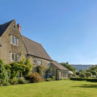 house with grey wall flowerbeds and lawns