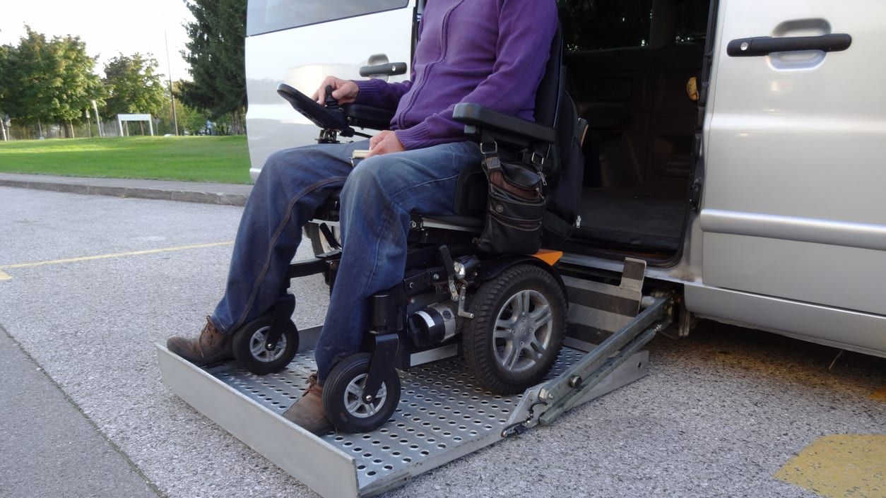 A man in a wheelchair on his car&amp;#039;s lift.