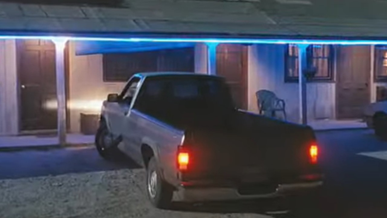 A truck parked outside of a tiny motel room in Bug