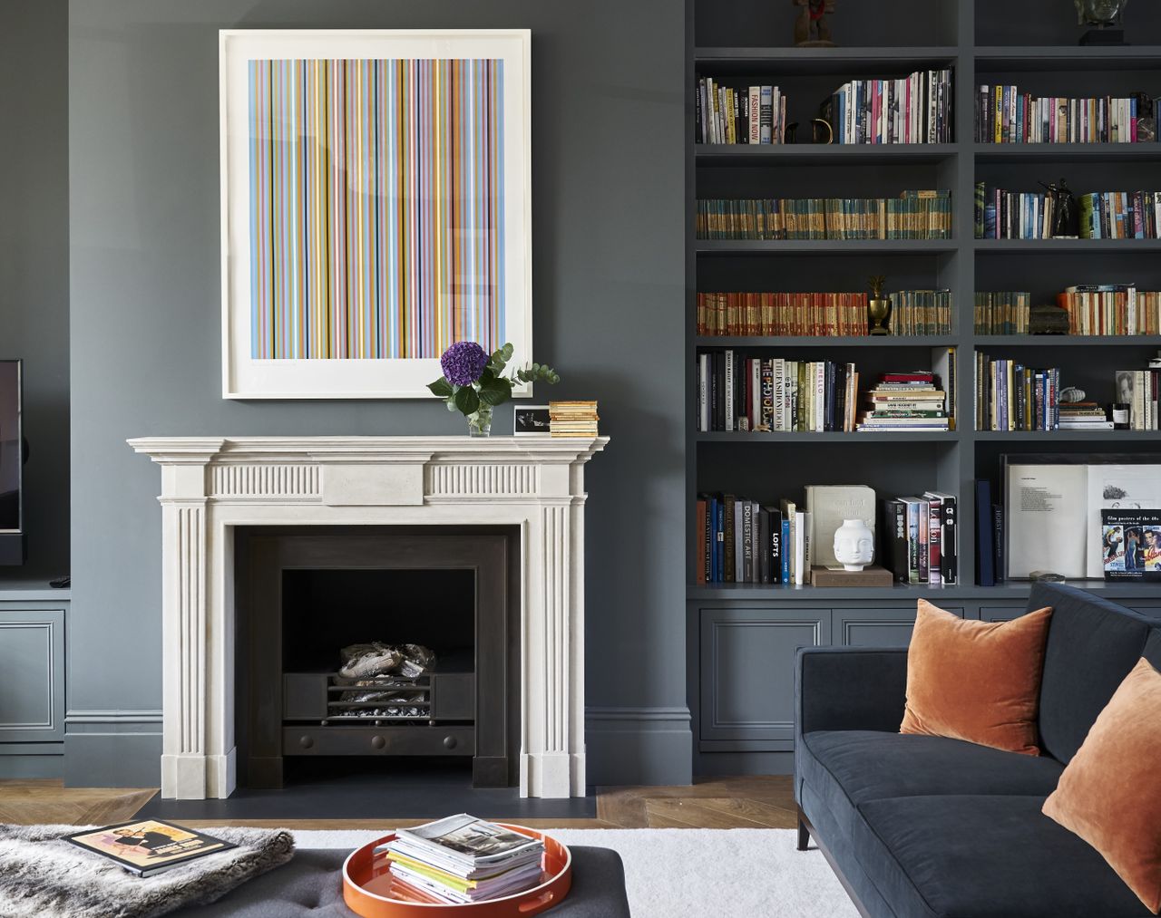 A living room in tones of grey, with couch pillows in orange