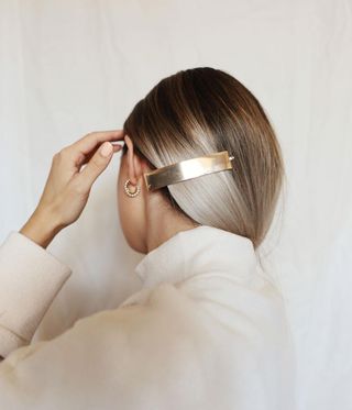 Back of a woman's head wearing a gold hair clip