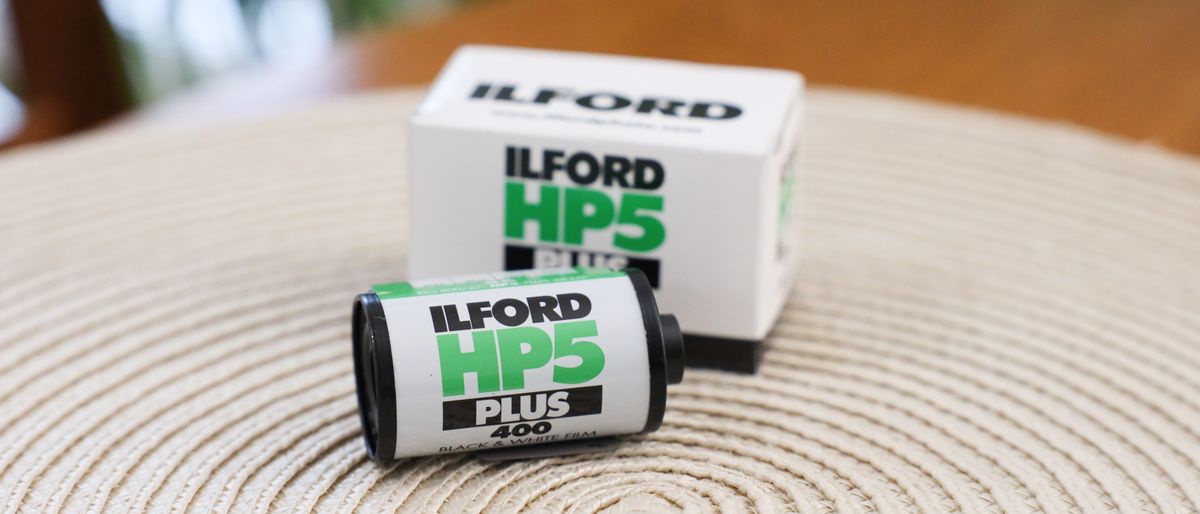 Ilford HP5 Plus 35mm film canister on a table next to it packaging box