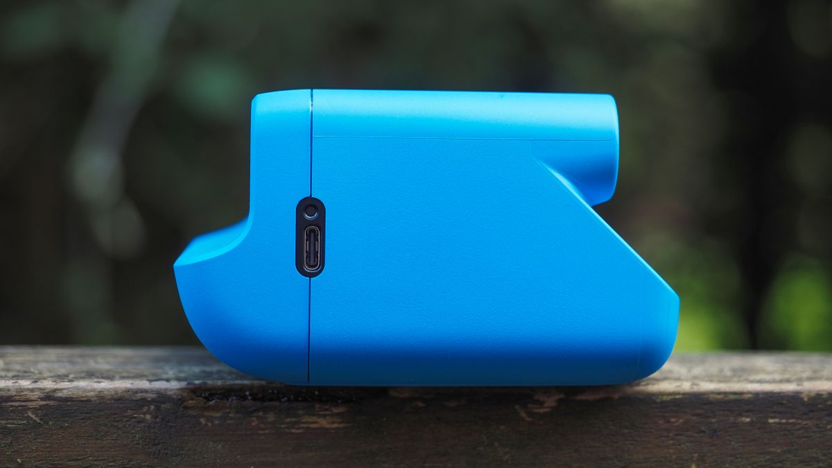 Blue Polaroid Go Gen 2 camera, on a wooden surface in a woodland setting