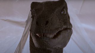 A raptor peeks out from under a plastic curtain in Jurassic Park.