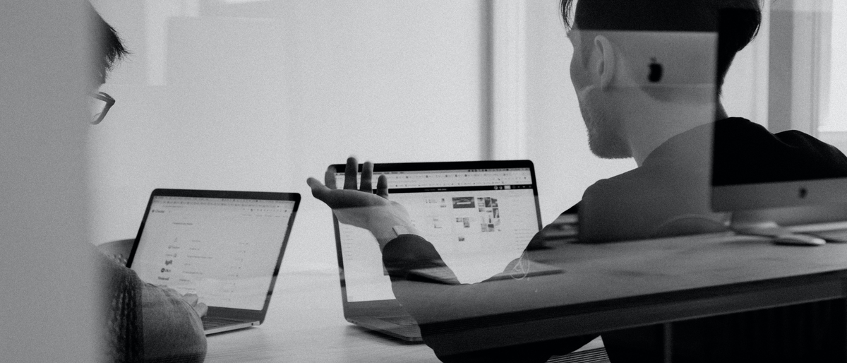 Two employees discussing work with two laptops