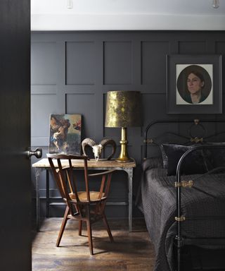 A bedroom with black painted panelled walls, a white ceiling and wooden floors