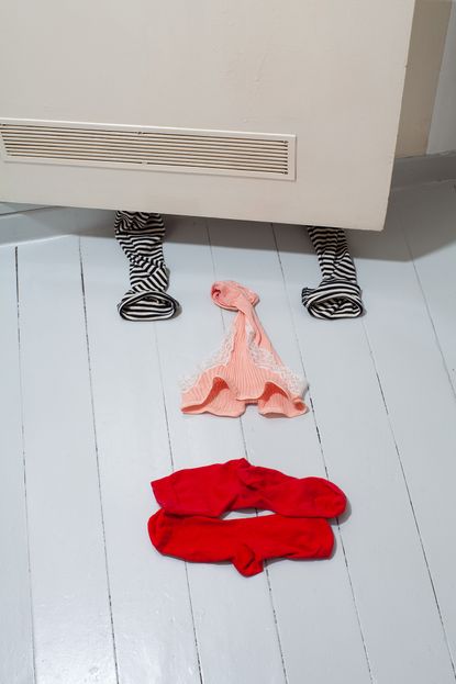 Socks and women's underwear on a floor in the shape of a face- eyes, nose, mouth