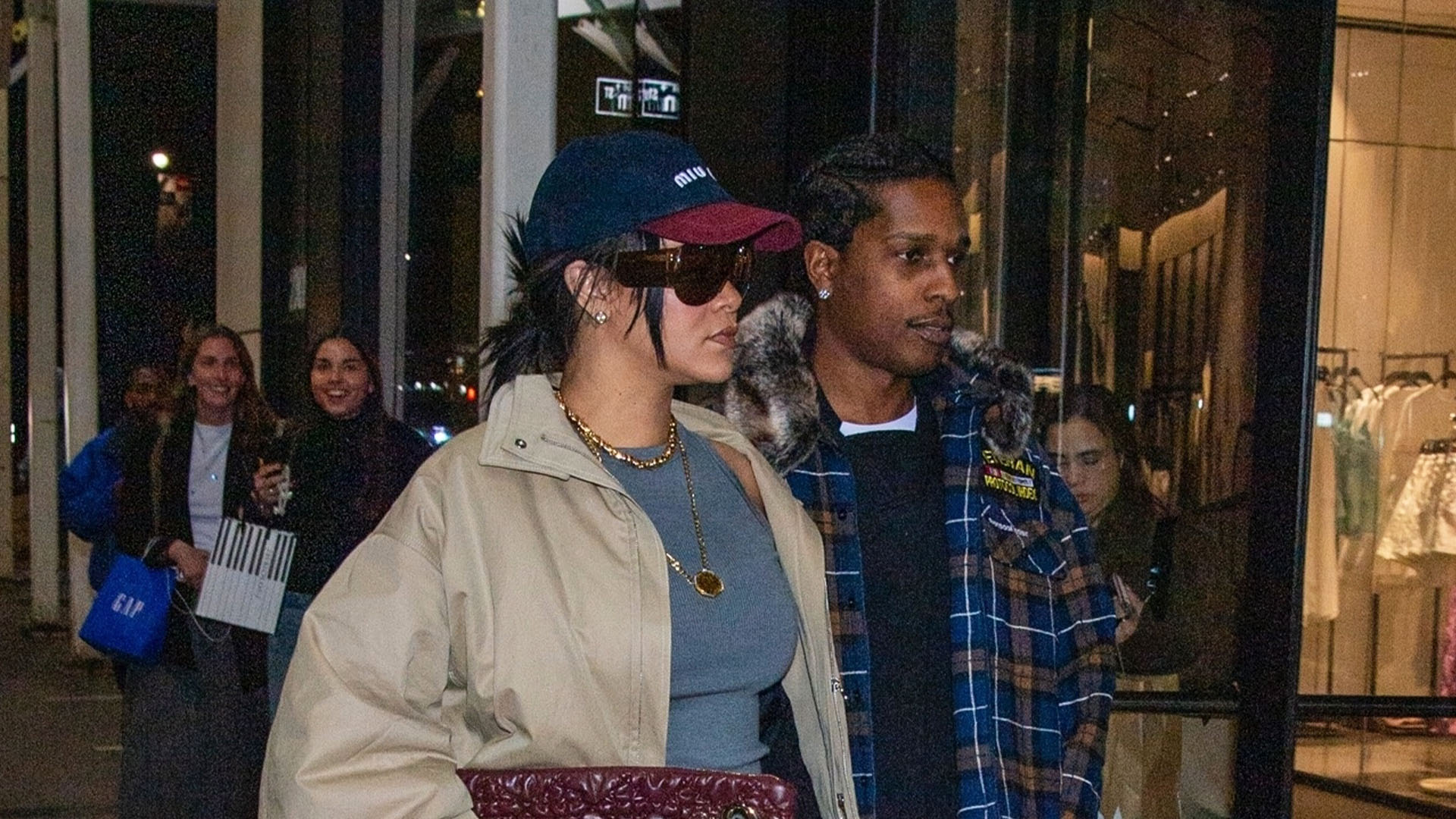 Rihanna wearing a two-toned Miu Miu baseball cap, gray tank top, black belt, black pants, burgundy Dior bag