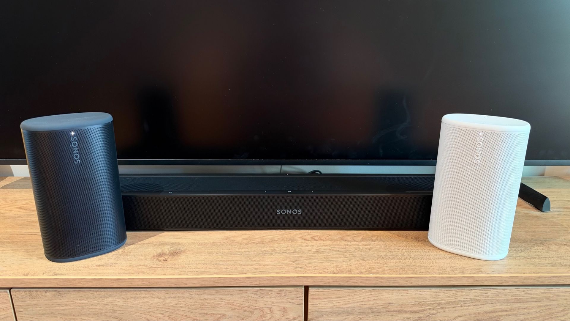 Sonos Beam Ultra with black and white Sonos Play speakers on a TV unit.