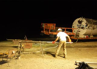 When a drill has gone deep enough to fill the core barrel, drilling stops and a cable winch pulls the barrel to the surface. A worker extracts the piece of core from the core barrel (seen here during the night shift), and the barrel is sent back down the hole to capture the next core section.