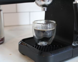 A double-walled espresso mug filled with espresso that has a thin layer of crema made using the Mr. Coffee Steam Espresso Maker
