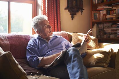 Portrait of a senior man sitting on the sofa reading a newspaper